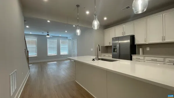 a large kitchen with stainless steel appliances a large counter top a stove and a refrigerator