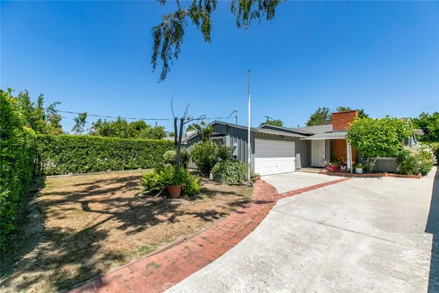 a front view of a house with a yard and potted plants