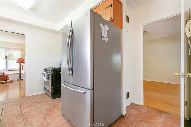 a view of a refrigerator in kitchen and a empty room