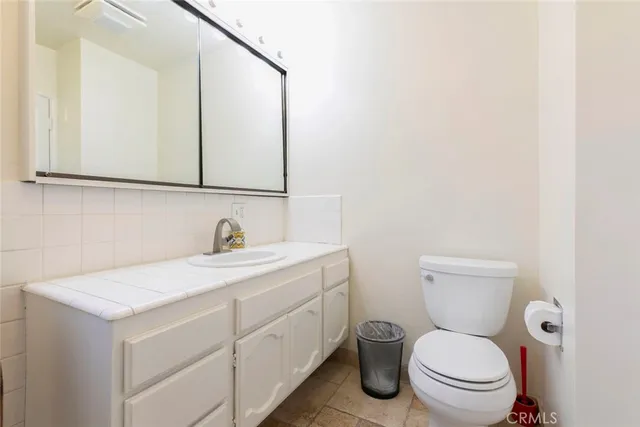 a bathroom with a toilet sink vanity and mirror
