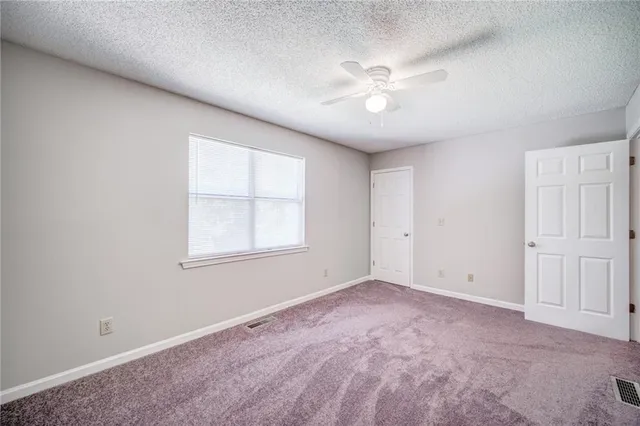 an empty room with chandelier fan and windows