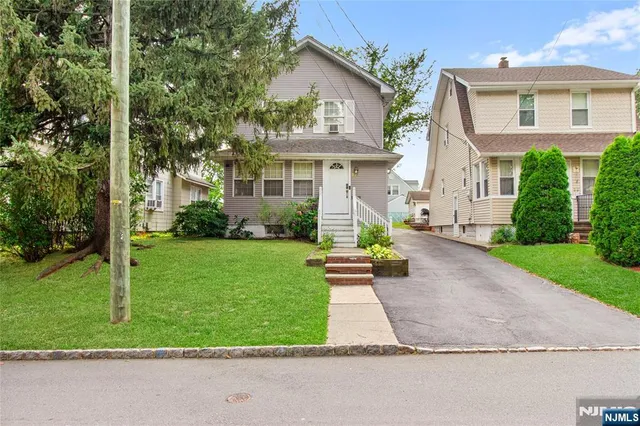 a front view of a house with a yard and potted plants