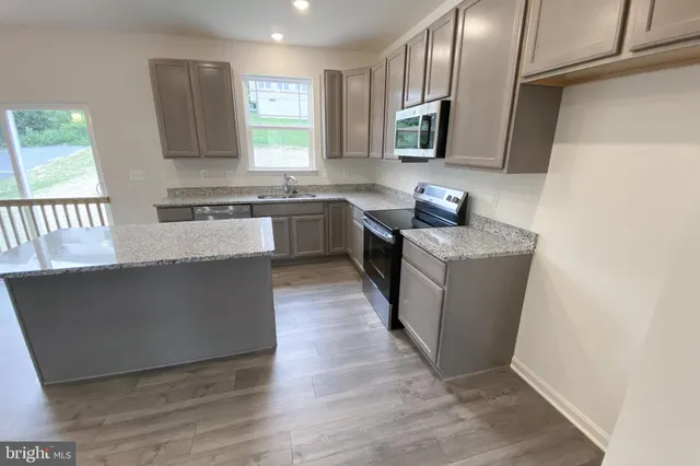 a kitchen with stainless steel appliances granite countertop a sink a stove top oven a counter space and cabinets