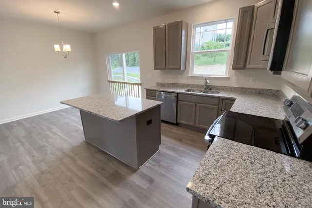 a kitchen with granite countertop cabinets a sink a window and stainless steel appliances