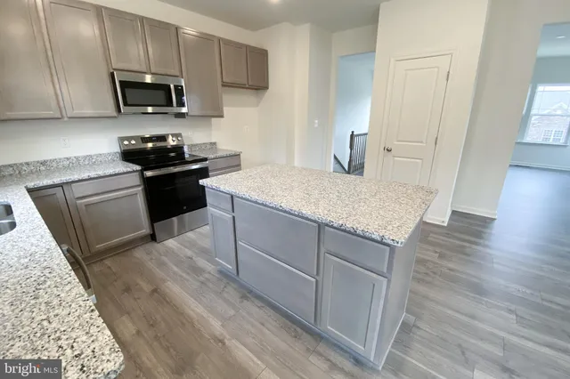 a kitchen with stainless steel appliances kitchen island granite countertop a stove a sink and a microwave