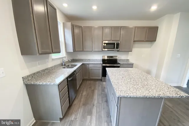 a kitchen with granite countertop a sink a counter top space stainless steel appliances and cabinets