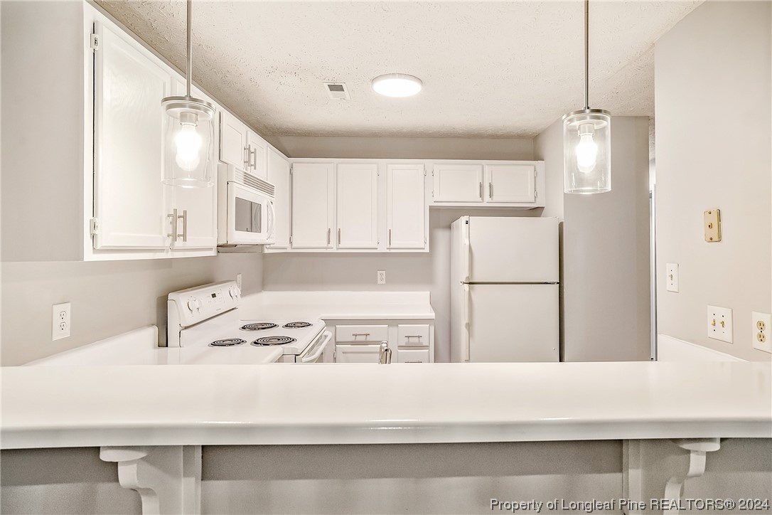 a kitchen with a refrigerator a white stove top oven sink and cabinets
