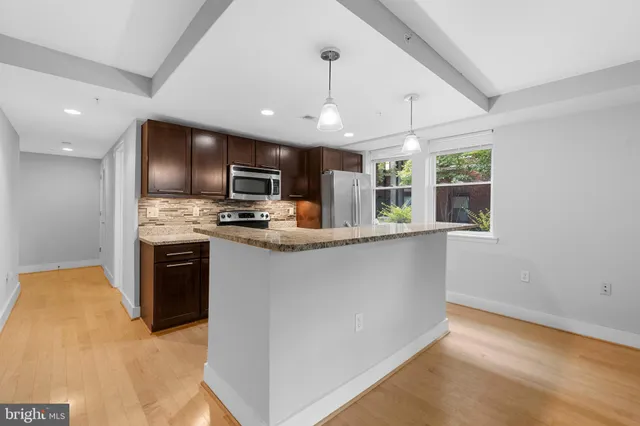 a kitchen with kitchen island granite countertop stainless steel appliances cabinets a sink and a counter top space