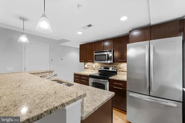 a kitchen with kitchen island a counter top space stainless steel appliances and cabinets