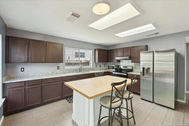 a kitchen with a sink a counter top space stainless steel appliances and cabinets