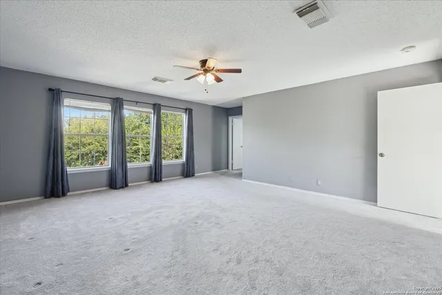 an empty room with windows and ceiling fan