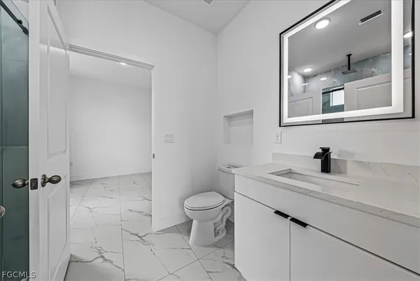 a bathroom with a sink a toilet a mirror and vanity