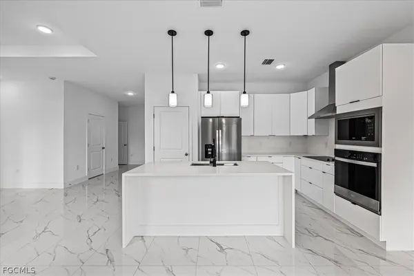 a large kitchen with stainless steel appliances kitchen island granite countertop a stove a sink and a microwave