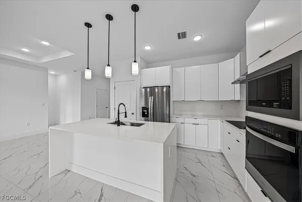 a kitchen with stainless steel appliances kitchen island granite countertop a sink a stove and a refrigerator