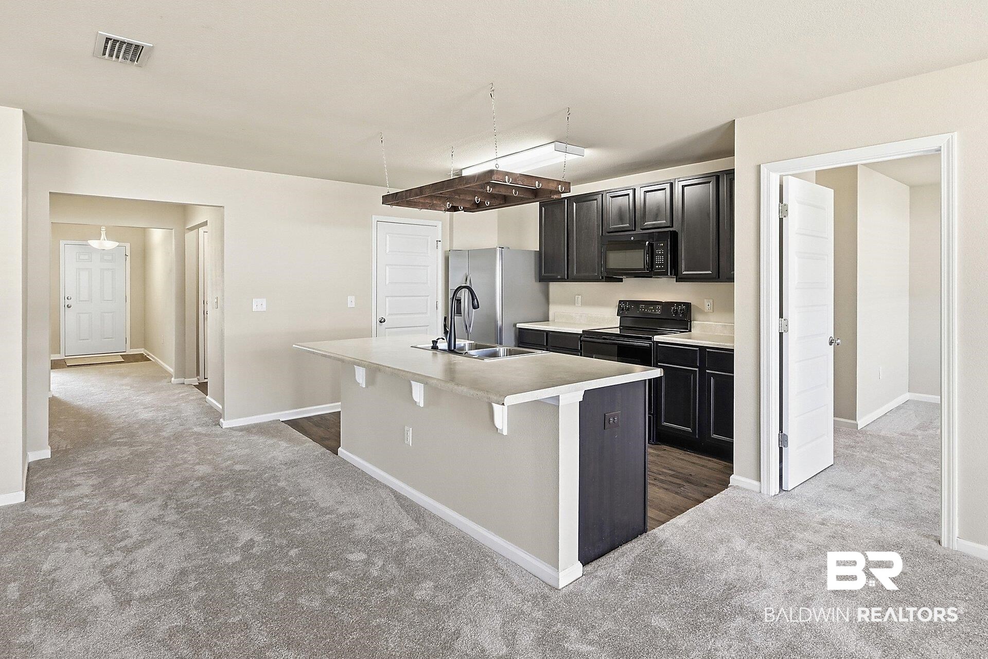 983 Summerton Drive Foley, AL 36535 - Photo 10 of 25 Kitchen featuring black appliances, light countertops, light carpet, a center island with sink, and a breakfast bar