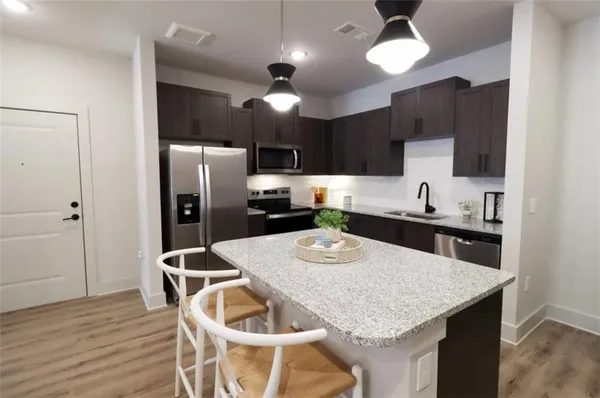 a kitchen with stainless steel appliances granite countertop a dining table chairs refrigerator and microwave