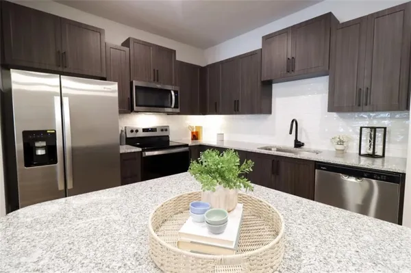a kitchen with granite countertop a sink stainless steel appliances and cabinets