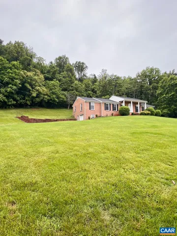 a view of a large pool with lawn chairs and a large tree