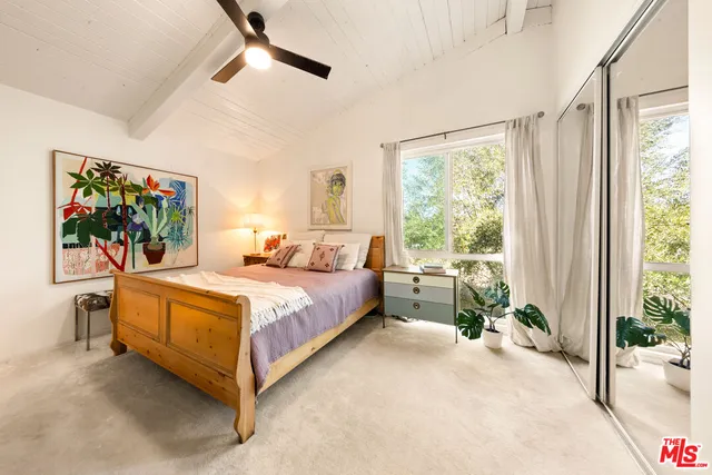 a bedroom with a bed and large windows