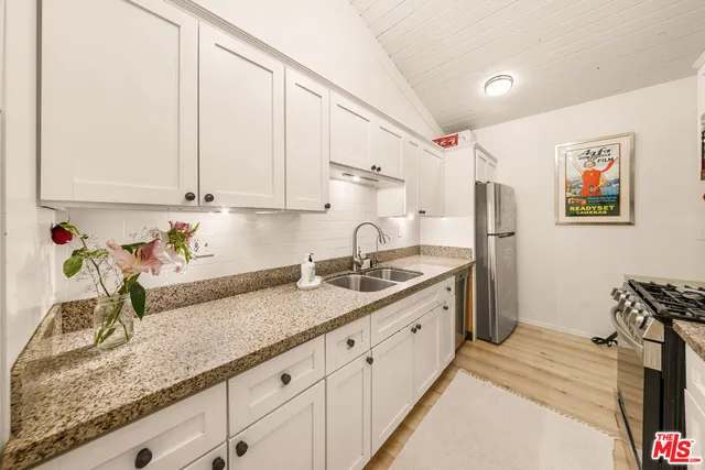 a kitchen with granite countertop a sink a stove and cabinets