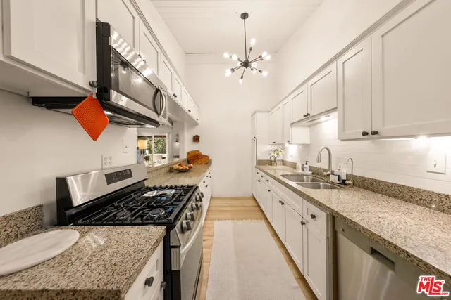 a kitchen with stainless steel appliances granite countertop a sink a stove oven a counter space and cabinets