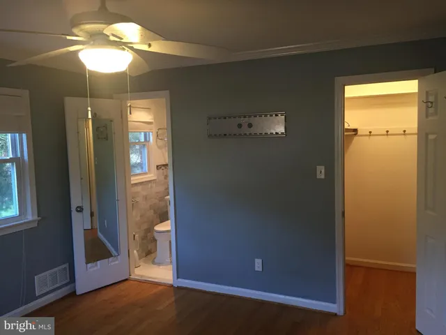 an empty room with chandelier fan and windows