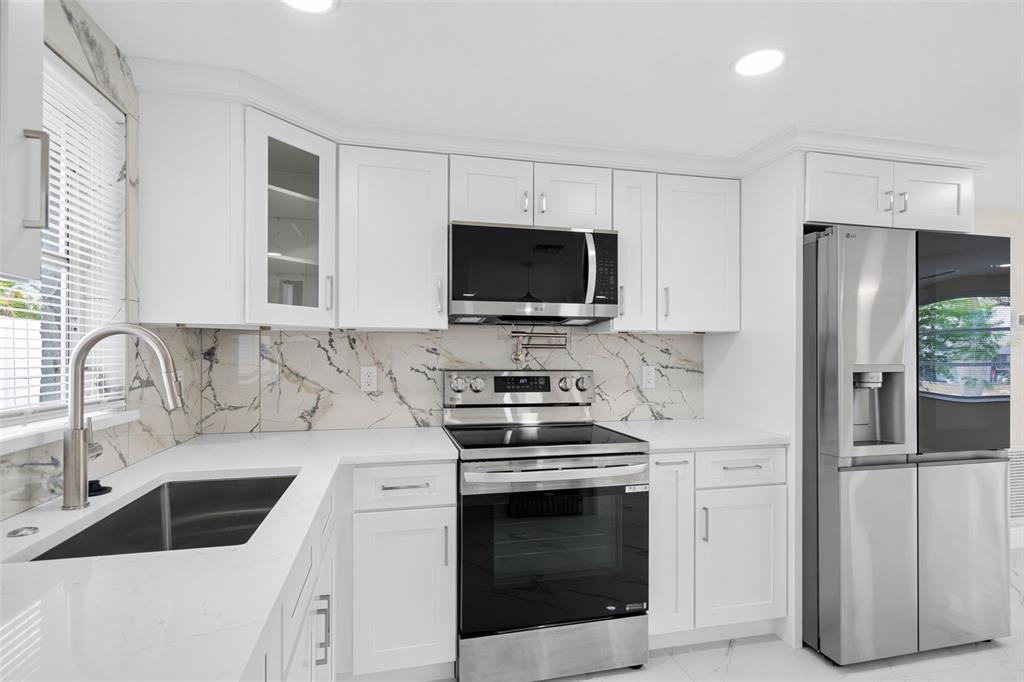 5626 Moog Road Holiday, FL 34690 - Photo 15 of 38 a kitchen with stainless steel appliances a stove a sink and a microwave