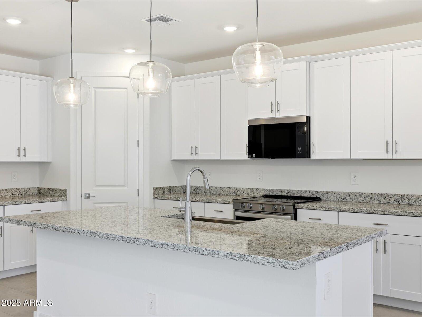 24477 West Grove Street Buckeye, AZ 85326 - Photo 1 of 49 a kitchen with stainless steel appliances granite countertop a sink a microwave oven a stove and white cabinets