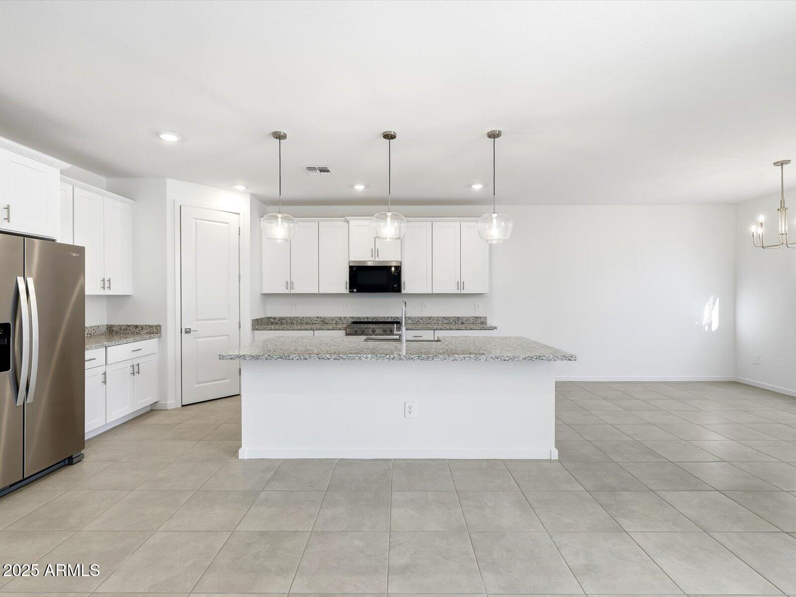 24477 West Grove Street Buckeye, AZ 85326 - Photo 11 of 49 a large kitchen with stainless steel appliances kitchen island granite countertop a refrigerator a stove and oven
