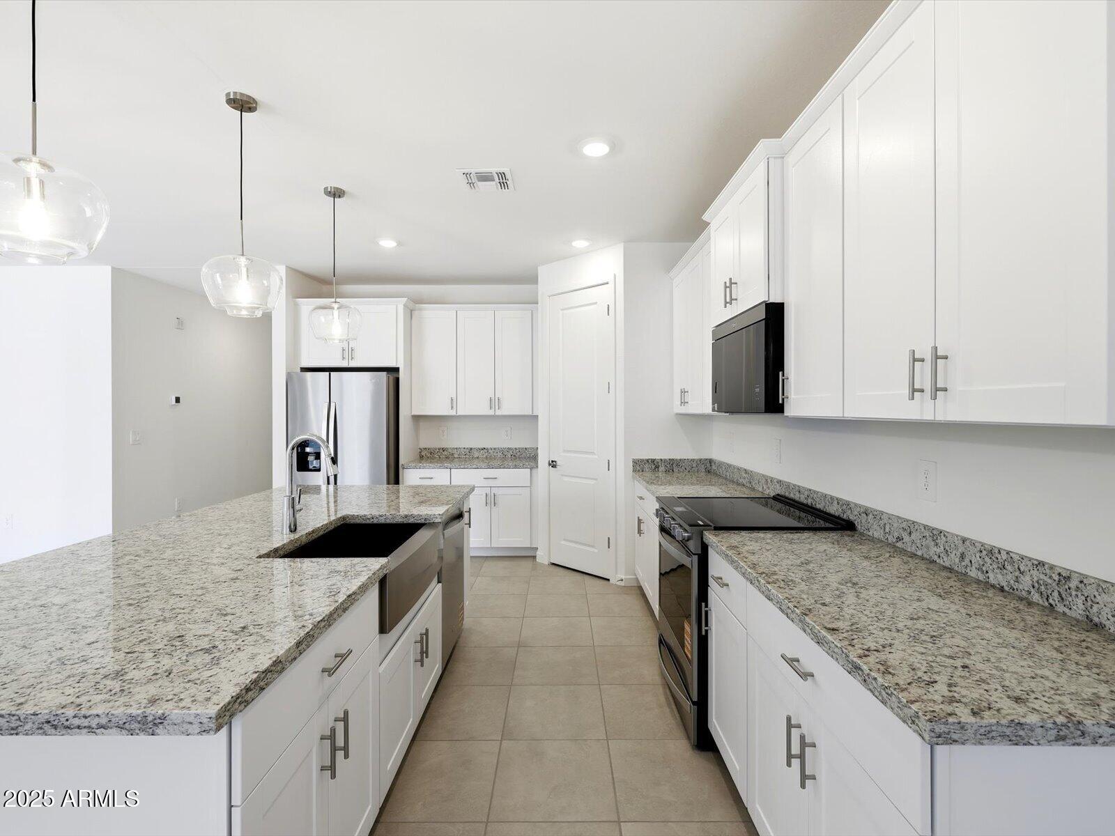 24477 West Grove Street Buckeye, AZ 85326 - Photo 5 of 49 a kitchen with stainless steel appliances granite countertop a sink a stove and a refrigerator