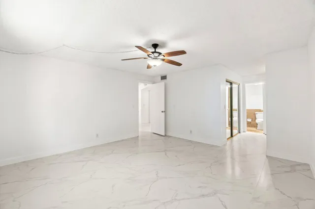 an empty room with chandelier fan and windows