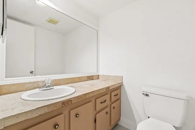 a bathroom with a granite countertop sink toilet and a mirror