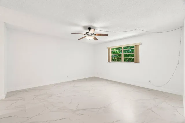 an empty room with a window and a ceiling fan