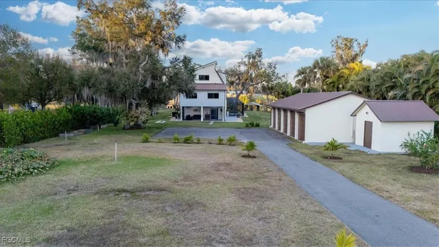 a view of a white house with a yard and table and chairs under an umbrella