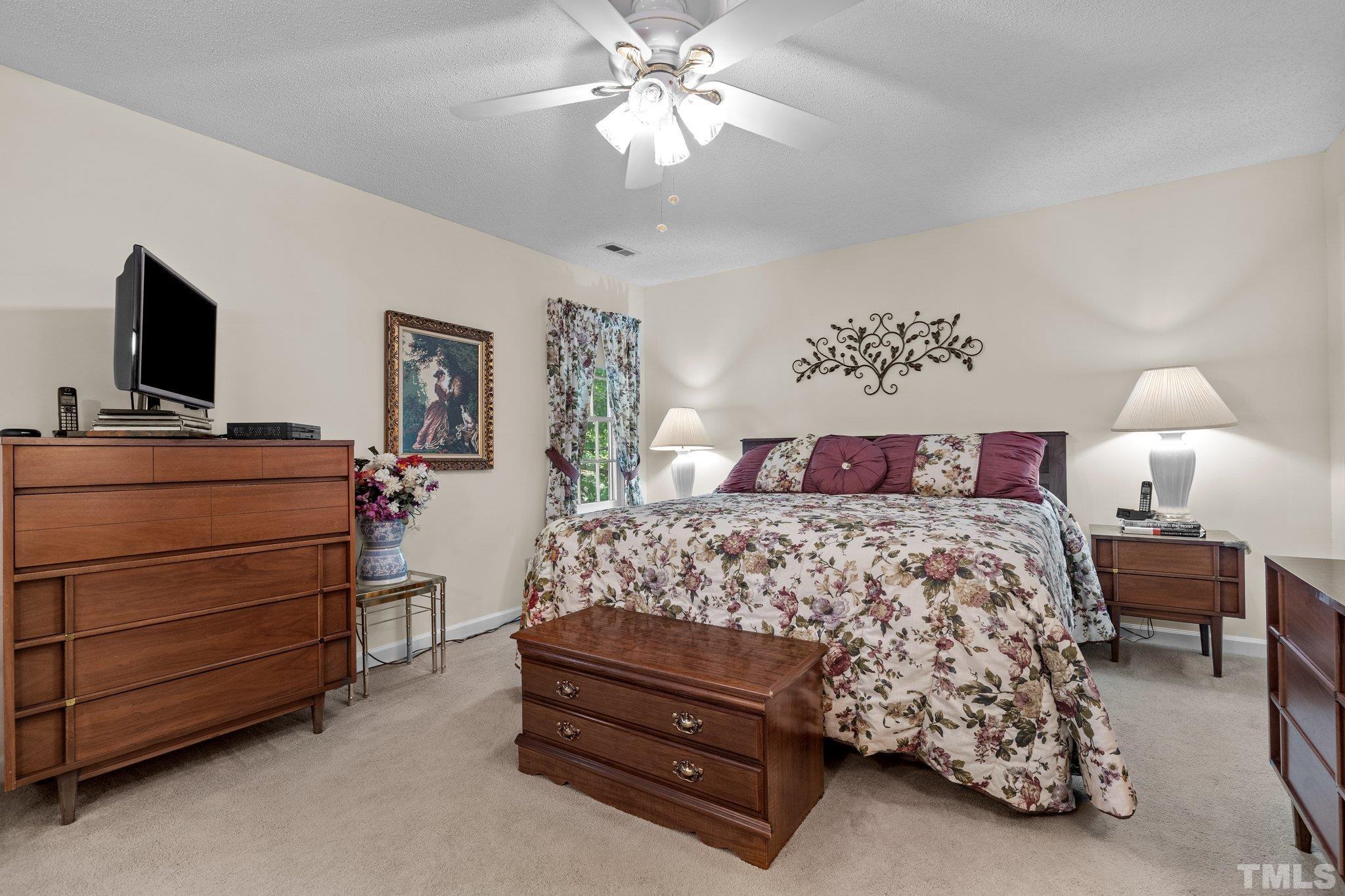 7805 Harps Mill Road Raleigh, NC 27615 - Photo 27 of 57 a bedroom with a bed and a flat tv screen on dresser