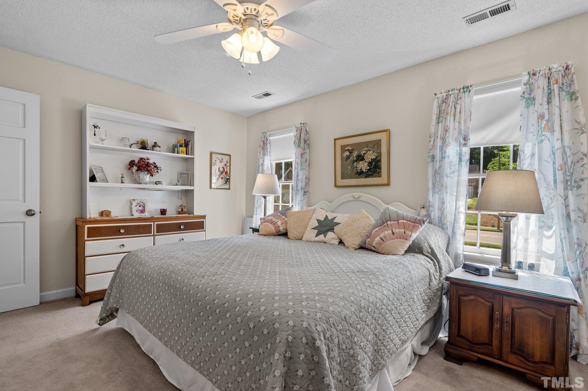 7805 Harps Mill Road Raleigh, NC 27615 - Photo 33 of 57 a bedroom with a large bed and a chandelier
