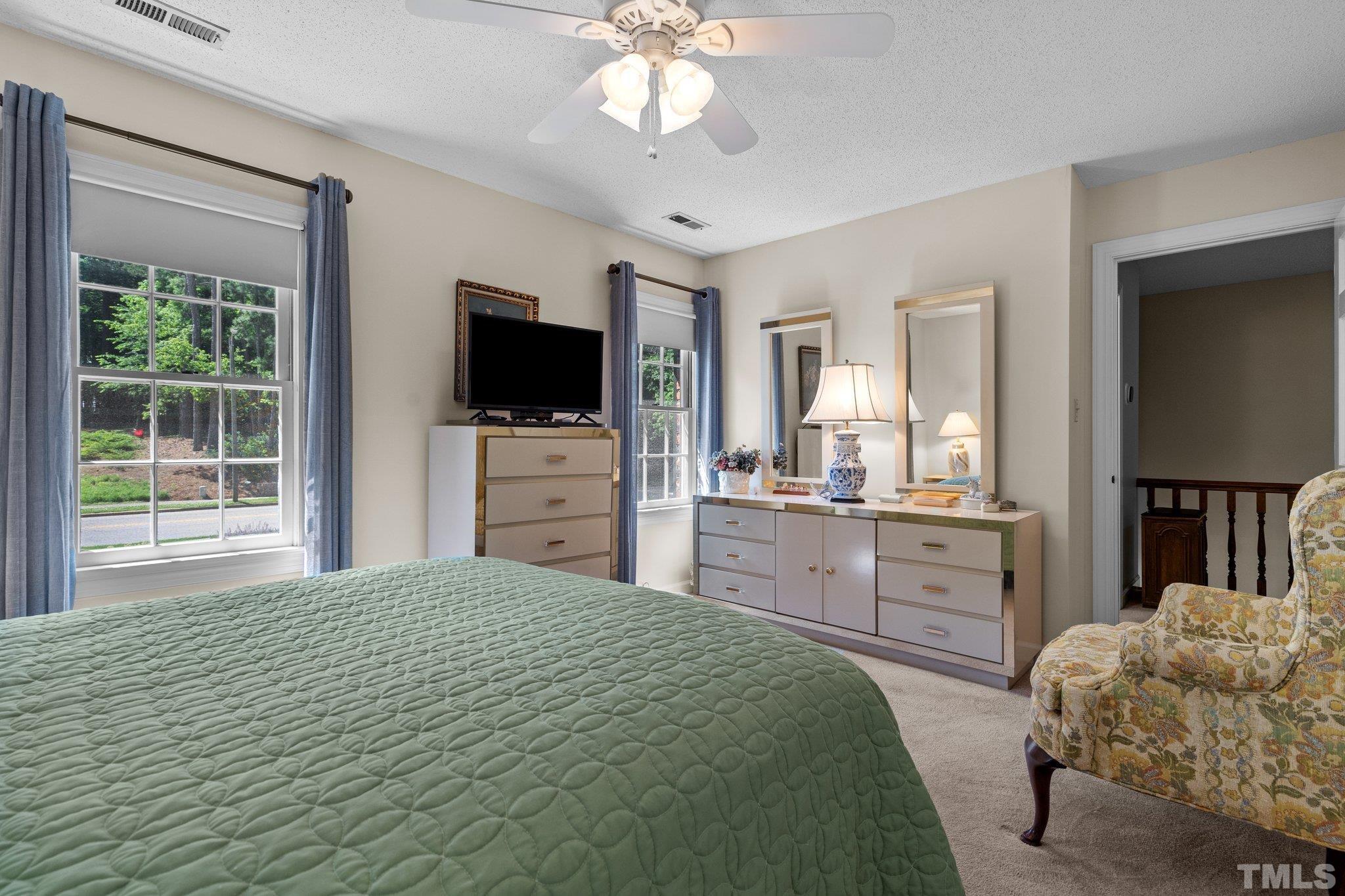 7805 Harps Mill Road Raleigh, NC 27615 - Photo 35 of 57 a bedroom with a large bed and a flat tv screen on dresser