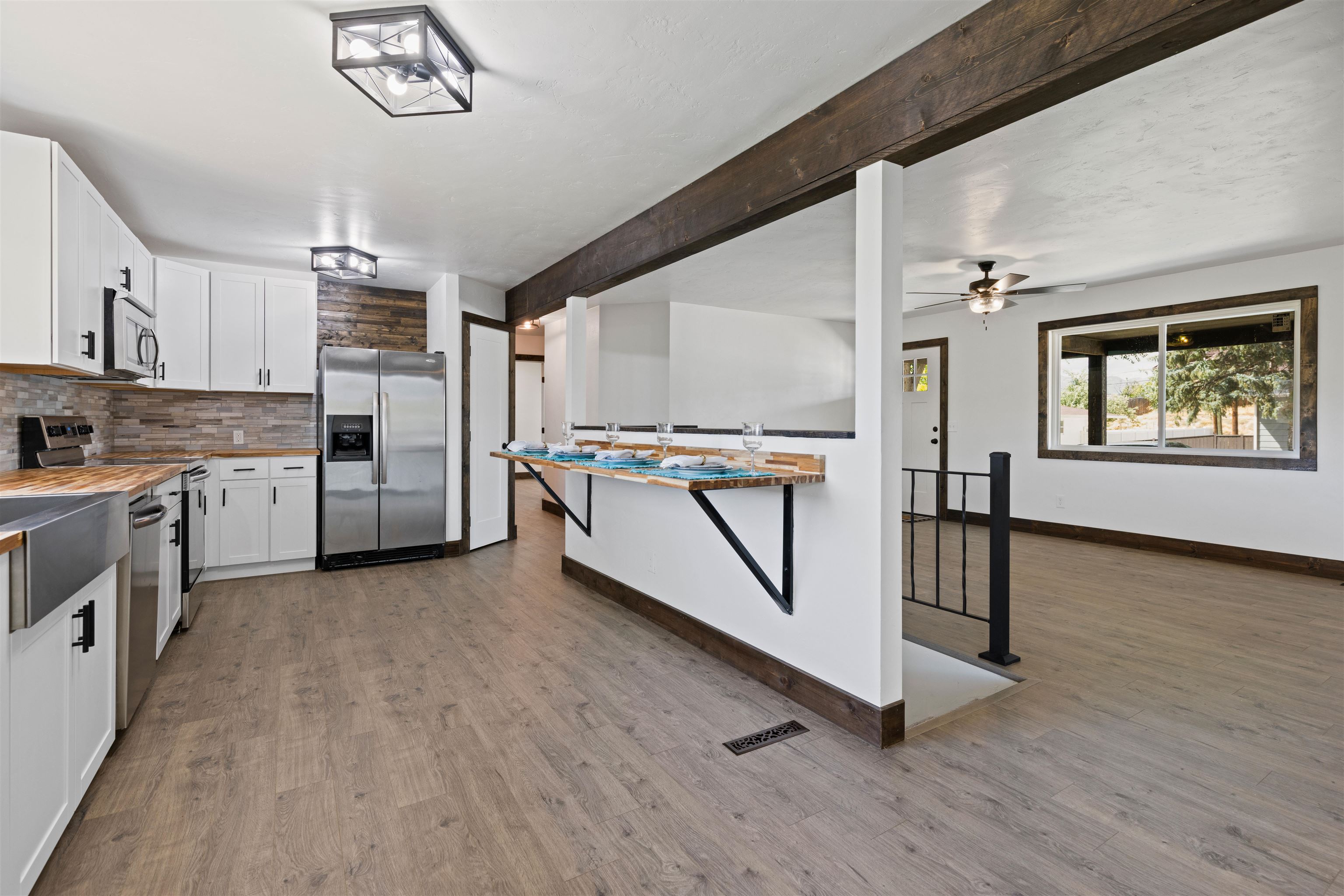 547 East 12th Street Rifle, CO 81650 - Photo 9 of 26 a kitchen with stainless steel appliances a refrigerator a sink dishwasher a stove and white cabinets with wooden floor