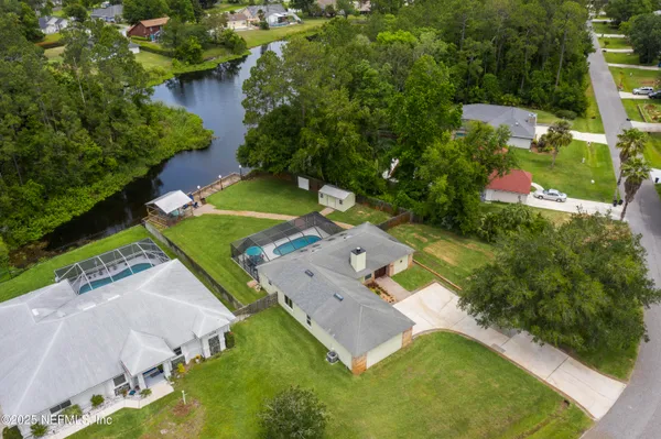 an aerial view of residential houses with outdoor space and trees