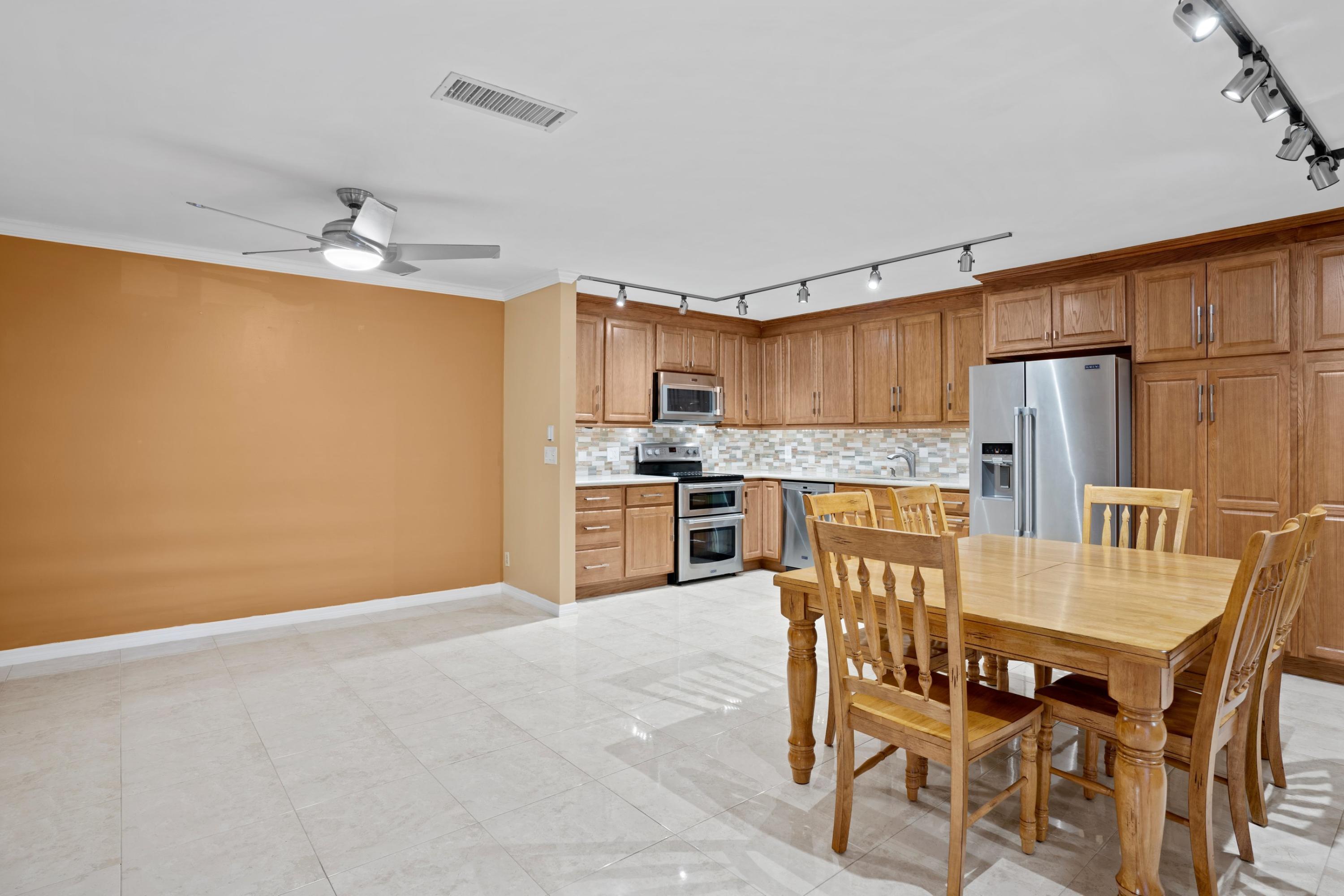 109 Woodland Road Palm Springs, FL 33461 - Photo 4 of 20 a kitchen with stainless steel appliances granite countertop a dining table chairs refrigerator and microwave