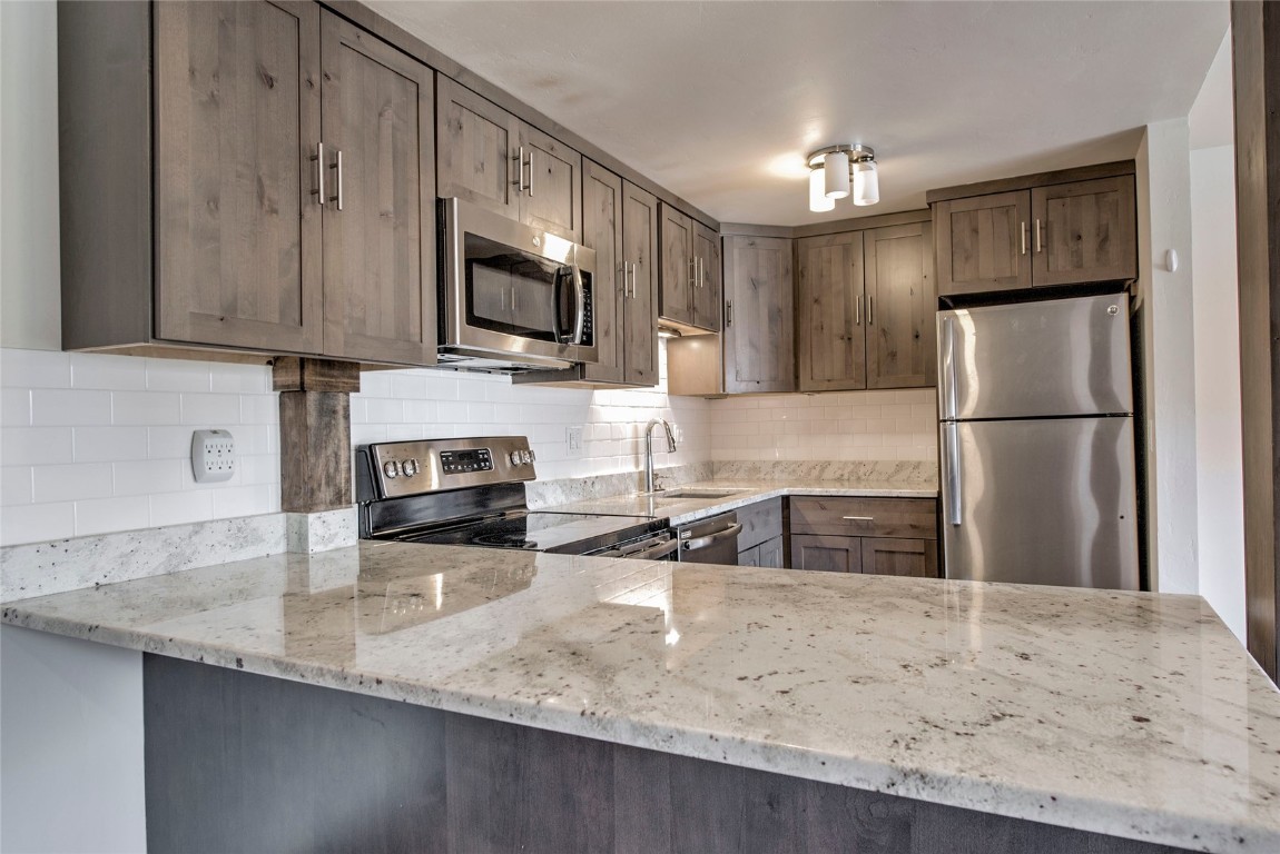 150 Evergreen Road, Unit 106 Dillon, CO 80435 - Photo 2 of 19 a kitchen with granite countertop a refrigerator a sink a stove a microwave and wooden cabinets