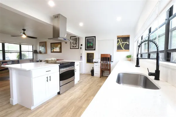a kitchen with stainless steel appliances kitchen island a white counter top space a sink and a large window