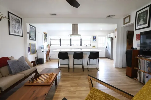a living room with furniture a rug and white kitchen view