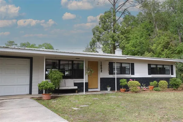 front view of a house with potted plants and a bench