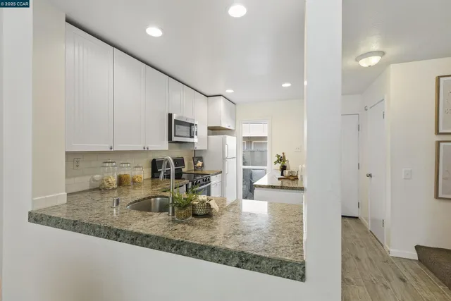 a kitchen with stainless steel appliances granite countertop a sink refrigerator and cabinets