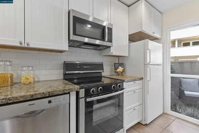 a kitchen with stainless steel appliances granite countertop a stove a refrigerator and a white cabinets