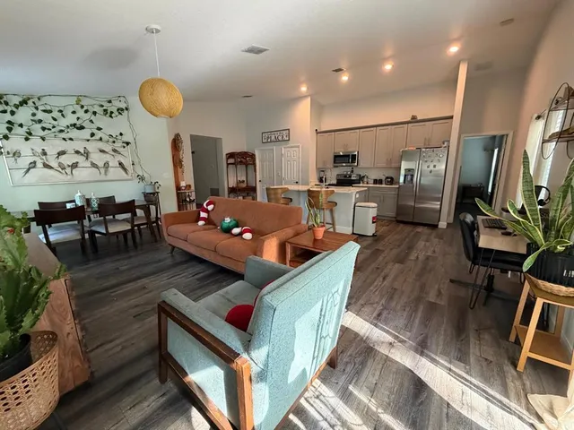 a kitchen with stainless steel appliances a refrigerator a stove a dining table and chairs with wooden floor