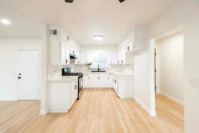 a kitchen with a refrigerator a sink and white cabinets