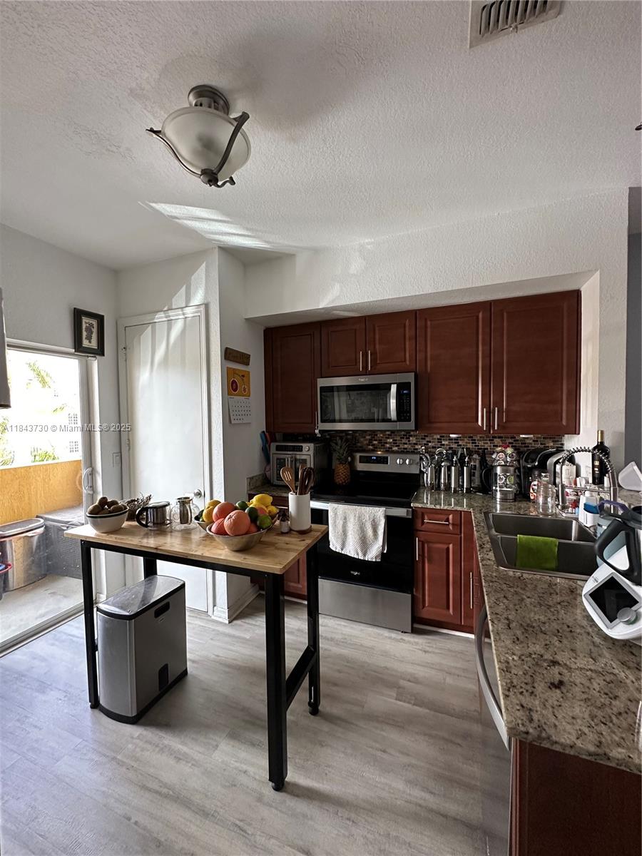 141 Northwest 2nd Avenue, Unit 2 Hallandale Beach, FL 33009 - Photo 4 of 21 a kitchen with a stove a sink and a refrigerator