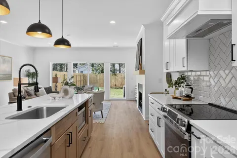 a kitchen with stainless steel appliances granite countertop a sink a stove and a wooden floors